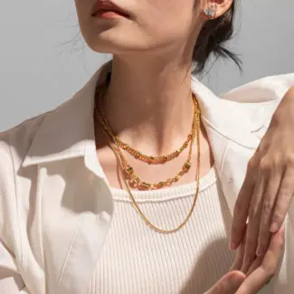 Three LIVKE gold layered necklaces with minimalist pendants, styled over a white tee for casual-chic everyday outfits.
