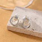 LIVKE’s silver geometric hoop earrings with triple coil layers, styled with a sleek bun for minimalist office elegance.