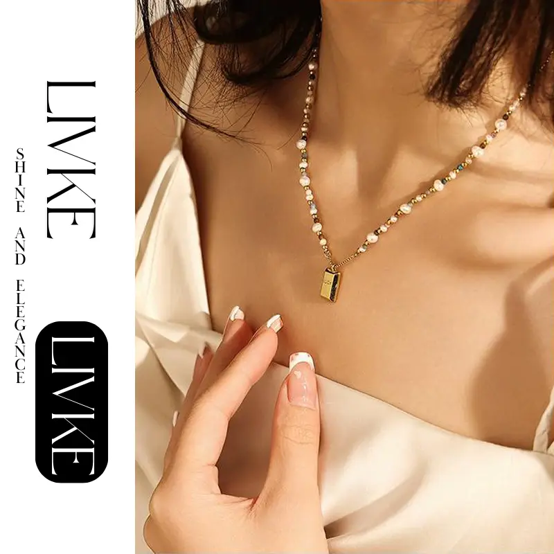 LIVKE’s gold French vintage ‘Luck’ pendant necklace with pearl drop, styled with a white blouse for office elegance.