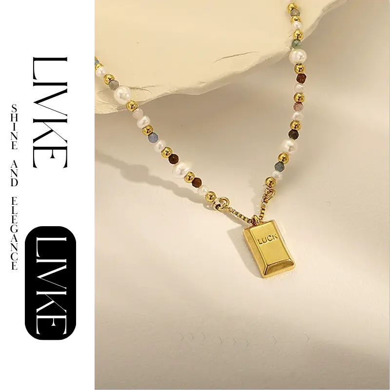 LIVKE’s gold French vintage ‘Luck’ pendant necklace with pearl drop, styled with a white blouse for office elegance.