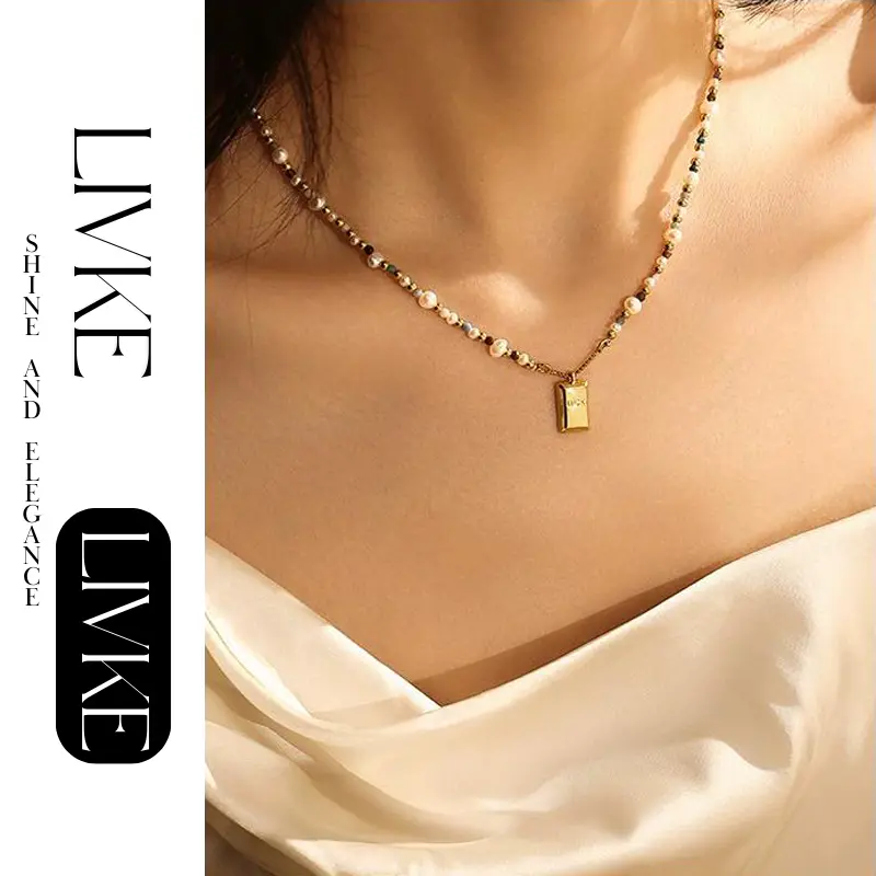 LIVKE’s gold French vintage ‘Luck’ pendant necklace with pearl drop, styled with a white blouse for office elegance.
