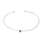 Model wearing LIVKE necklace with black CZ and pearl pendants on collarbone