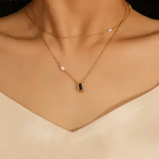 Model wearing LIVKE necklace with black CZ and pearl pendants on collarbone