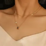 Model wearing LIVKE necklace with black CZ and pearl pendants on collarbone