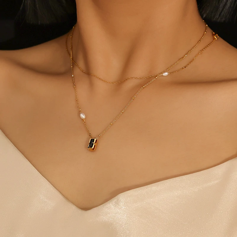 Model wearing LIVKE necklace with black CZ and pearl pendants on collarbone