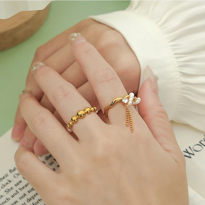 Hand wearing LIVKE adjustable pearl tassel ring at desert festival, showcasing boho jewelry with flowing movement