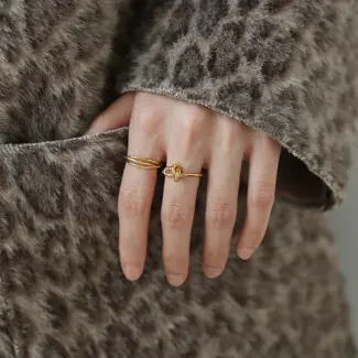 Three layered brass rings with spiral/chain/wave designs in 18K gold plating, stacked on a wooden tray for boho style