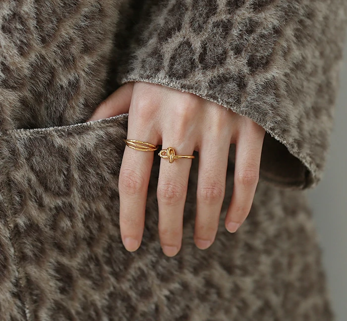 Three layered brass rings with spiral/chain/wave designs in 18K gold plating, stacked on a wooden tray for boho style