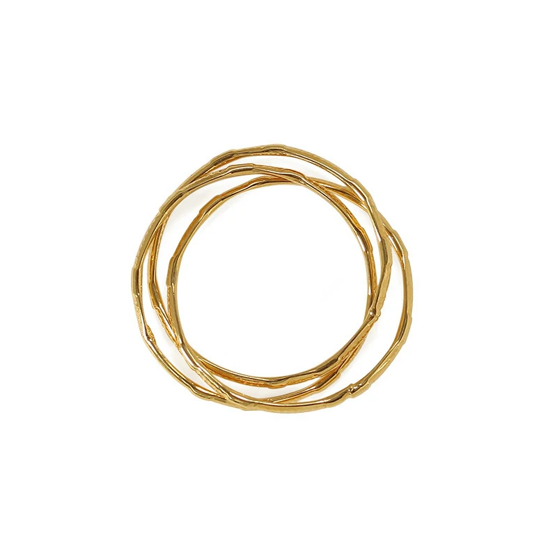 Three layered brass rings with spiral/chain/wave designs in 18K gold plating, stacked on a wooden tray for boho style