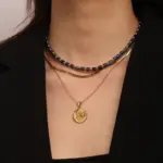Gold sun and moon pendants layered on model with white linen shirt