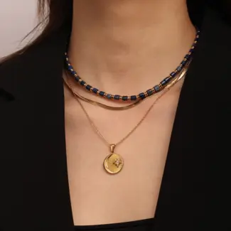 Gold sun and moon pendants layered on model with white linen shirt