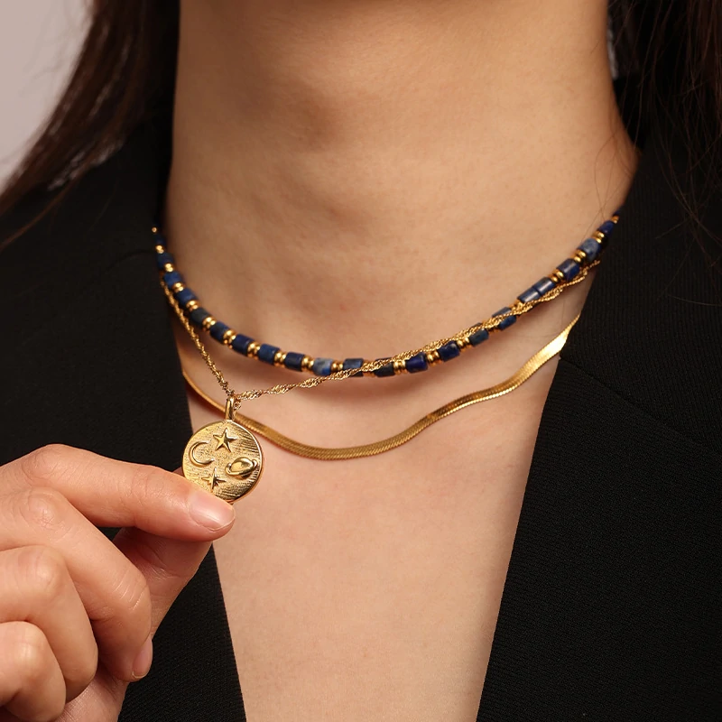 Gold sun and moon pendants layered on model with white linen shirt