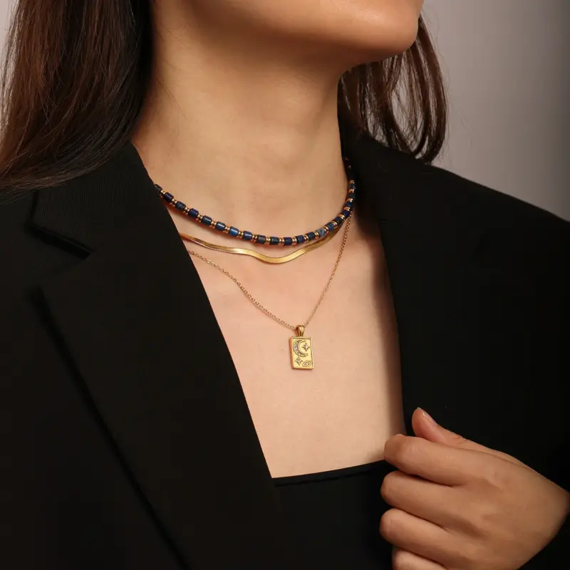 Gold sun and moon pendants layered on model with white linen shirt
