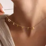 Gold alphabet necklace layered with 4 initials 'LIVK' on collarbone