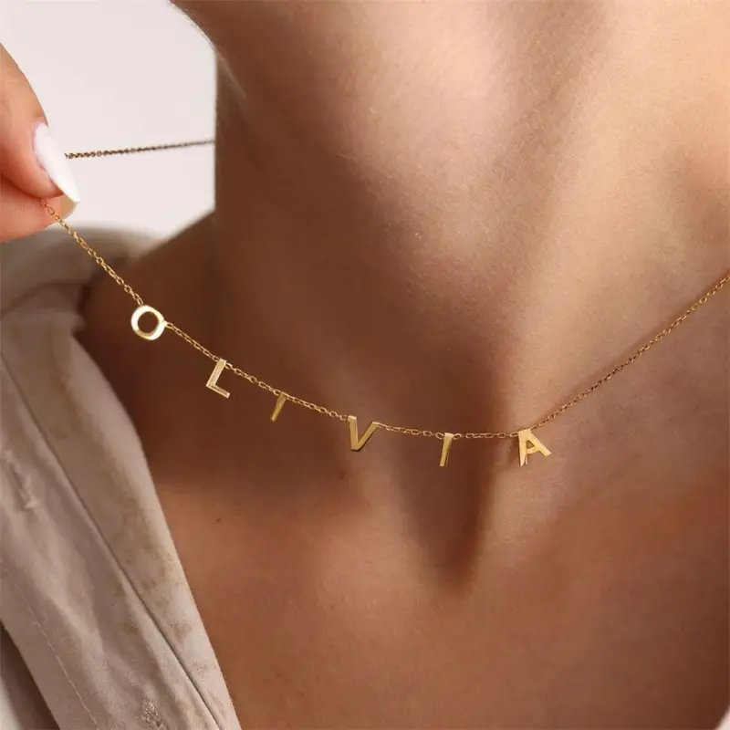 Gold alphabet necklace layered with 4 initials 'LIVK' on collarbone