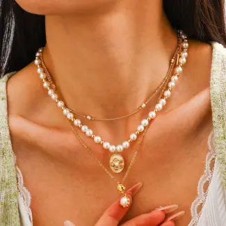 Woman wearing LIVKE gold plated pearl necklace with silk blouse and tailored blazer, showcasing vintage-inspired office to evening jewelry
