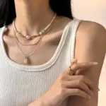 Woman wearing LIVKE green aventurine and white jade necklace with cashmere sweater, showcasing minimalist jewelry for urban elegance