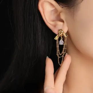 Gold knotted earrings with rainbow tassels on model dancing under club lights