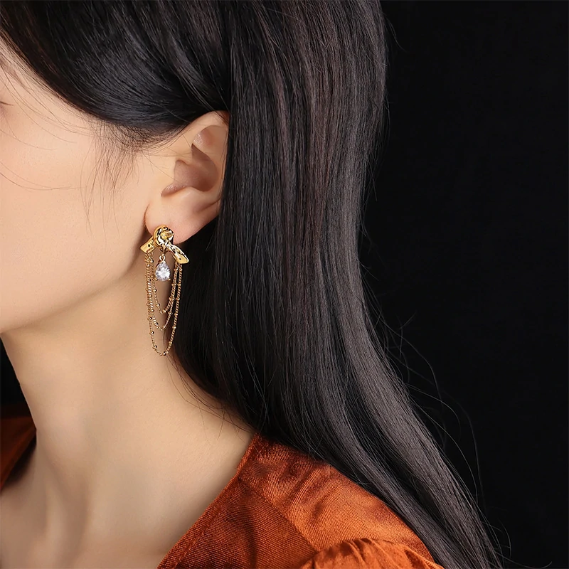 Gold knotted earrings with rainbow tassels on model dancing under club lights