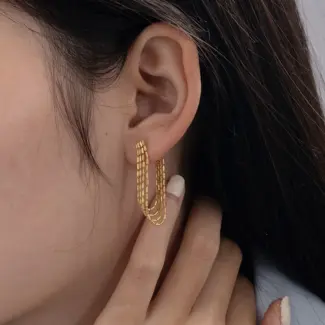 Model tilting head to showcase gold chain drops catching sunlight