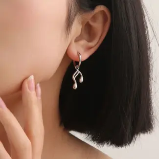 Gold note-shaped ear cuff on model's ear with sheet music background