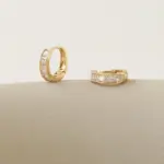 Gold ear cuff with square CZ stones on model's ear catching sunlight