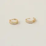 Gold ear cuff with square CZ stones on model's ear catching sunlight