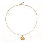 Natural tumbled shell pendant on 18K gold-plated chain styled with linen shirt and jeans at beachside café