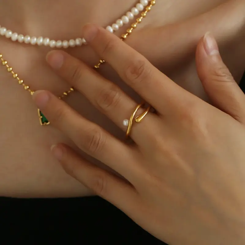 Hand model adjusting open wave ring with pearl under golden hour sunlight