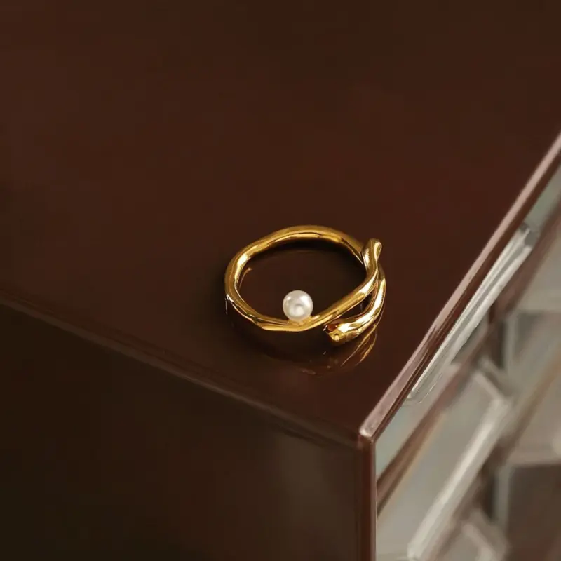 Hand model adjusting open wave ring with pearl under golden hour sunlight