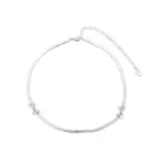 Bride wearing LIVKE white gold bow necklace with off-shoulder wedding dress, showcasing elegant bridal jewelry under sunset light