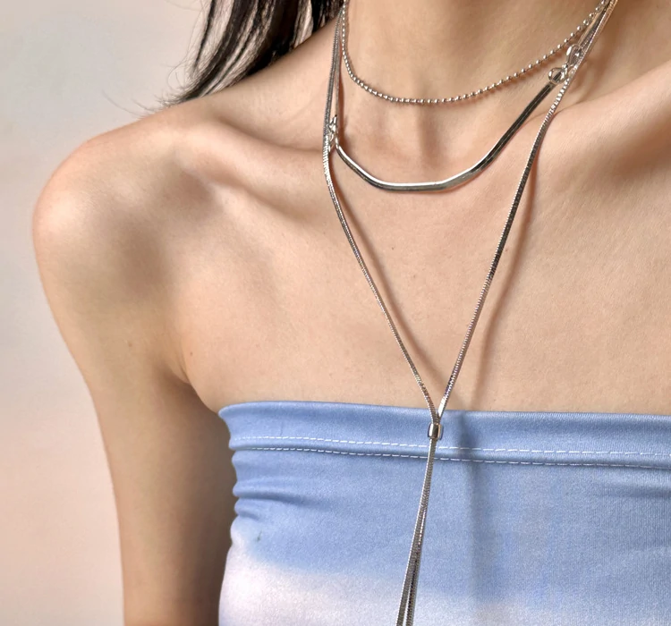 Bride wearing LIVKE white gold bow necklace with off-shoulder wedding dress, showcasing elegant bridal jewelry under sunset light