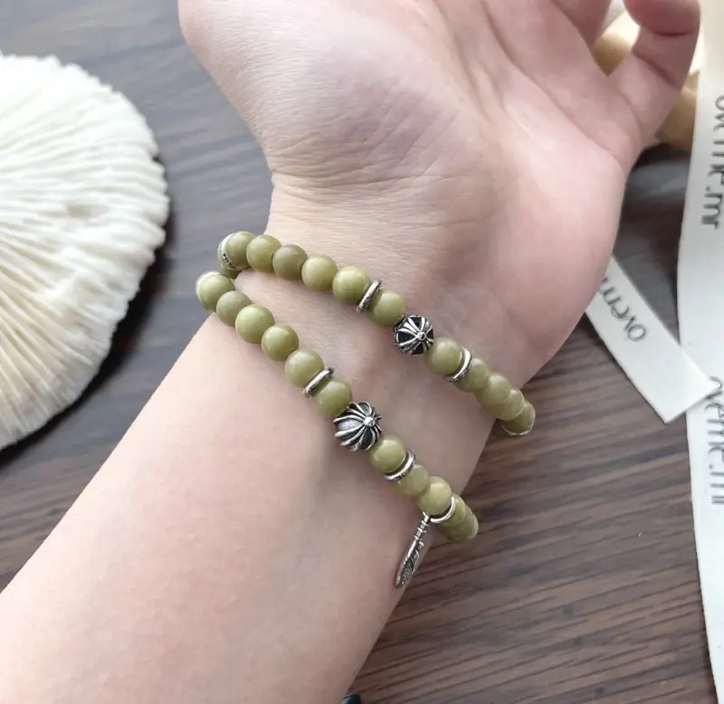Olive green aventurine bead bracelet with silver feather charm and floral spacer beads, designed for spiritual healing and crystal energy jewelry lovers